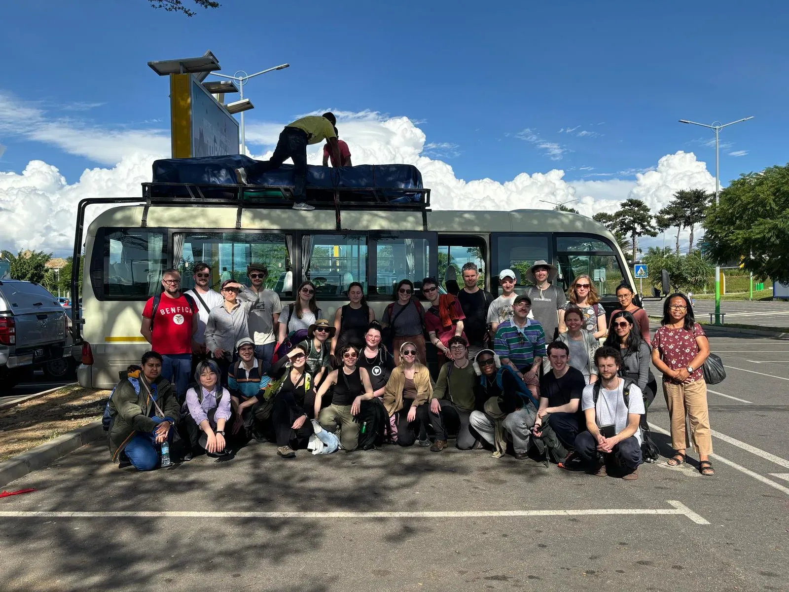 Group photo of master students and Kew staff members on the first day in Madagascar. Image credit - Isabel Larridon A group of people posing for a photo in front of a bus