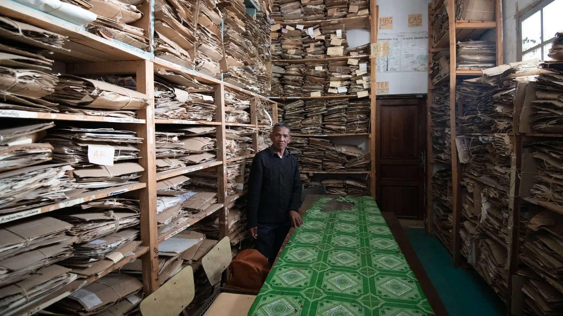 Herbarium collections at Kew Madagascar. Jeff Eden © RBG Kew Person standing in a room with stacks of cardboard