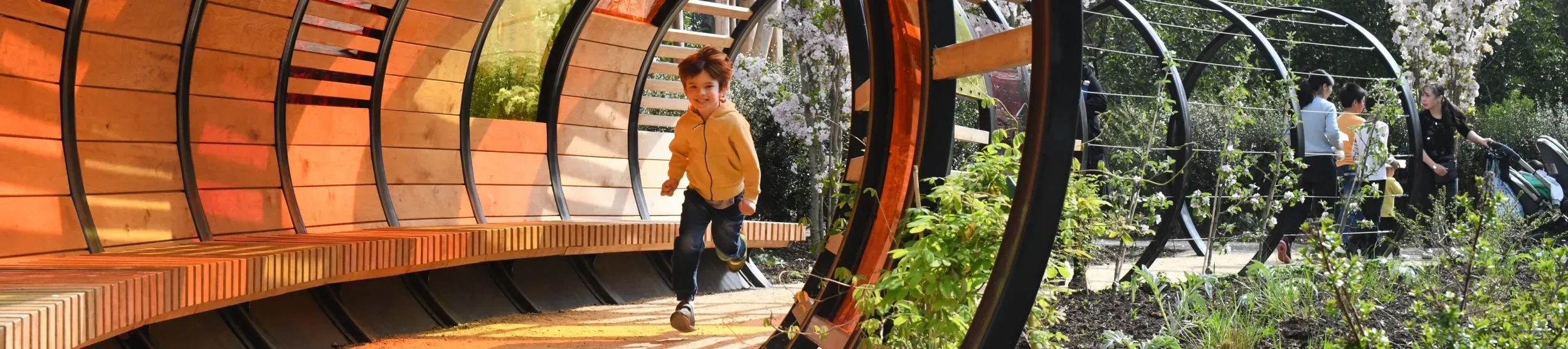 Children's Garden by Ines Stuart-Davidson © RBG Kew Young boy running through a wooden tunnel in the sun