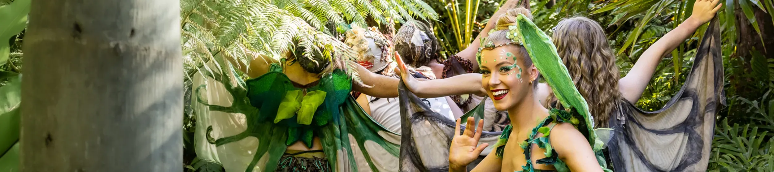The Dream Fairies - Adventure to Bubble Land © Australian Shakespeare Company A smiling fairy surrounded by other fairies in the green undergrowth