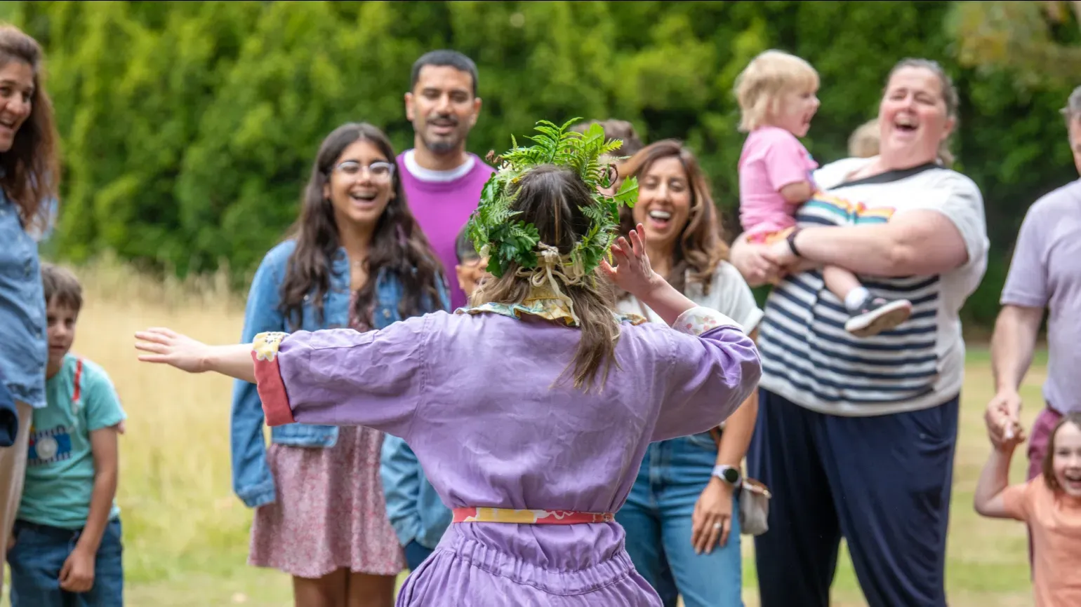 Oaklore at Kew Gardens, Ines Stuart-Davidson © RBG Kew A person in a purple jump suit performing to a group of children and adults