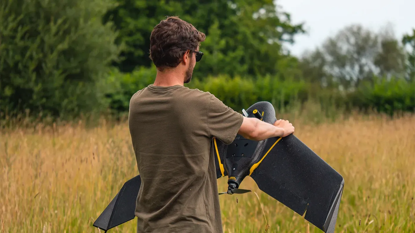 Spatial Analysis research, Visual Air © RBG Kew A scientist stands in a field holding a fixed wing drone